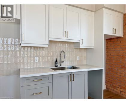 A kitchen with white cabinets and a brick wall.