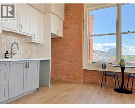A kitchen with a large window overlooking a residential area.