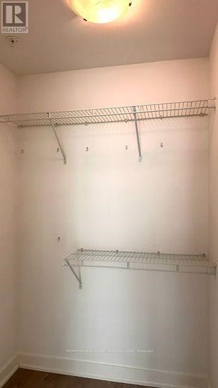 A white closet with two shelves and a light on.