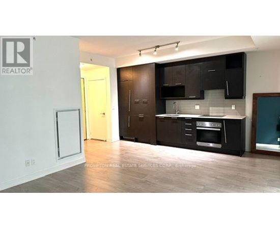 A kitchen with black cabinets and a wooden floor.