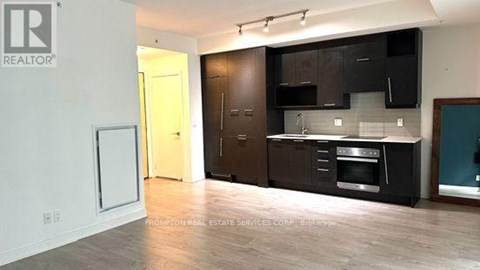 A kitchen with black cabinets and a wooden floor.