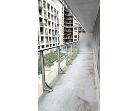 A long, narrow walkway with a metal railing and a building with balconies in the background.