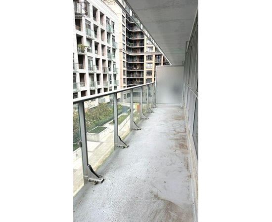 A long, narrow walkway with a metal railing and a building with balconies in the background.