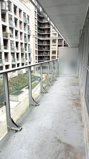 A long, narrow walkway with a metal railing and a building with balconies in the background.