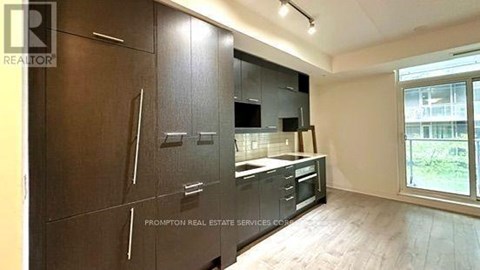 A kitchen with dark wood cabinets and a window overlooking a green area.