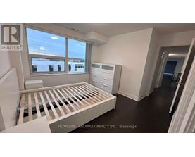 A room with a bed, dresser, and window with a view of buildings outside.