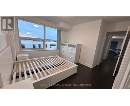 A room with a bed, dresser, and window with a view of buildings outside.