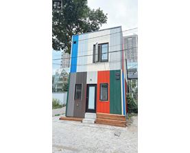 A small house with a blue, grey, green, and red exterior.