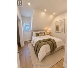 A bedroom with a bed covered in a white comforter and a green throw.