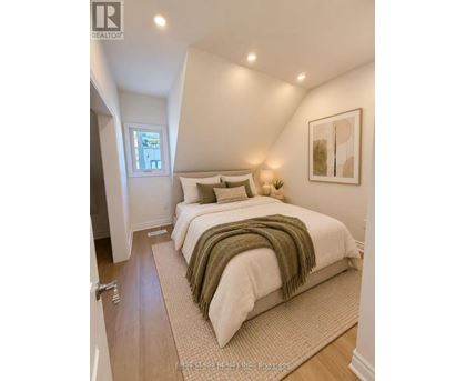 A bedroom with a bed covered in a white comforter and a green throw.