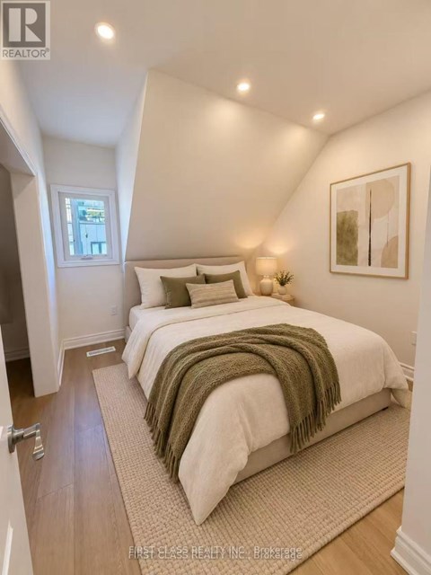 A bedroom with a bed covered in a white comforter and a green throw.