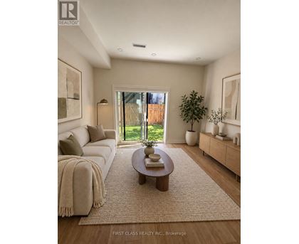 A well-lit living room with a large window and a view of a fence and greenery outside.