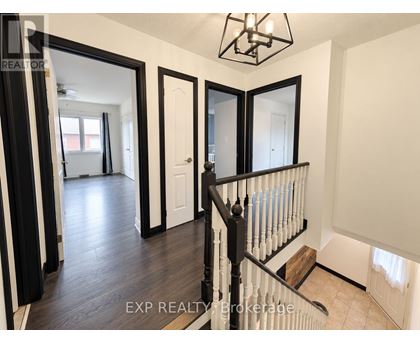 A hallway with a black railing and white walls.
