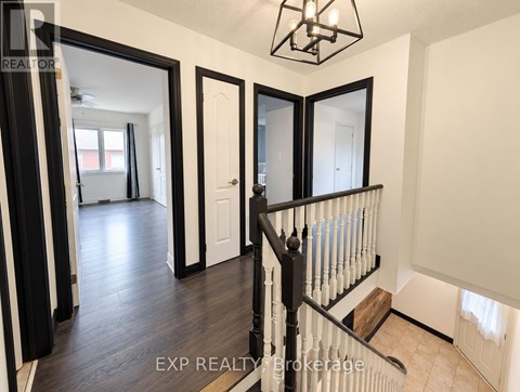 A hallway with a black railing and white walls.