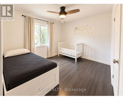 A bedroom with a bed, a crib, and a ceiling fan.