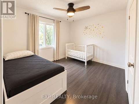 A bedroom with a bed, a crib, and a ceiling fan.