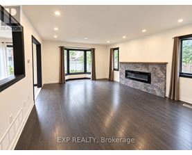 A spacious living room with wood flooring and a fireplace.