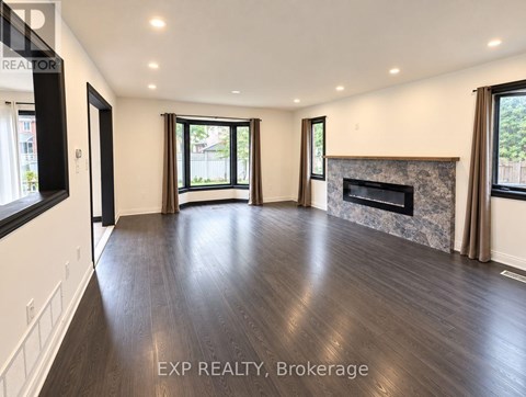 A spacious living room with wood flooring and a fireplace.