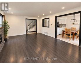A spacious room with wooden flooring and a dining area in the background.