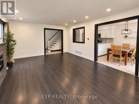 A spacious room with wooden flooring and a dining area in the background.