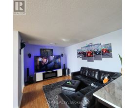 A black leather couch sits in front of a television in a living room.