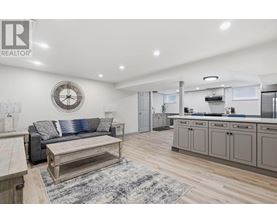 A well-lit kitchen and living room with a clock on the wall.
