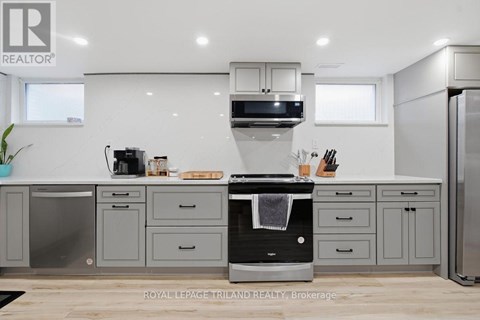 A modern kitchen with a black oven and grey cabinets.