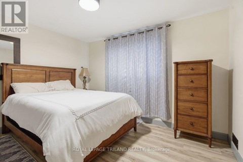 A bedroom with a large bed, a nightstand, and a wooden wardrobe.