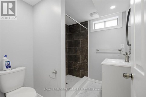 A white toilet sits next to a white sink in a bathroom.