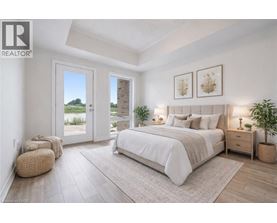 A bedroom with a large bed, a window with a view, and a plant on the side table.