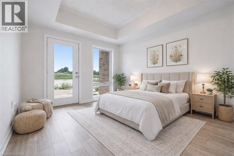 A bedroom with a large bed, a window with a view, and a plant on the side table.