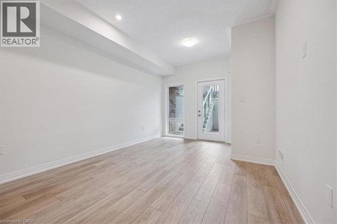 A spacious room with wooden flooring and a sliding glass door.