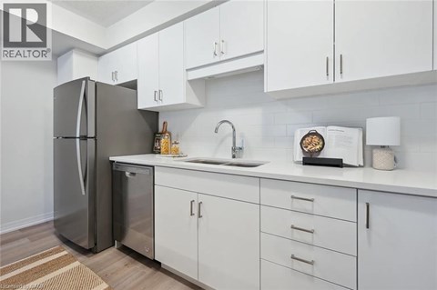 A modern kitchen with white cabinets and a stainless steel refrigerator.