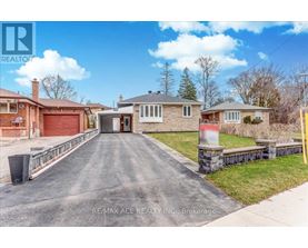 A real estate company's photo of a residential property with a driveway leading to a garage.