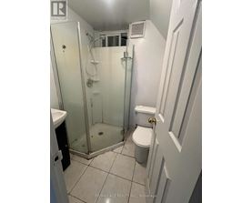 A white bathroom with a toilet, sink, and shower.