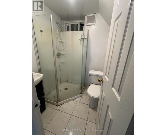 A white bathroom with a toilet, sink, and shower.