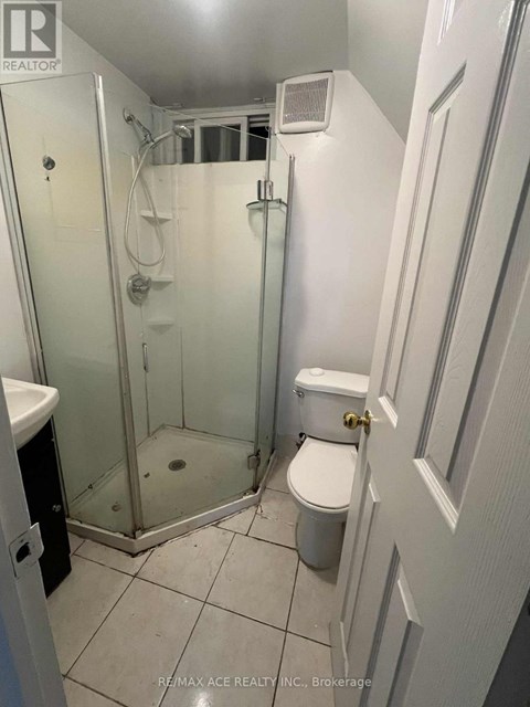 A white bathroom with a toilet, sink, and shower.