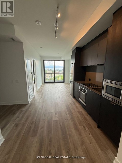 A modern kitchen with dark wood cabinets and a view of the city.