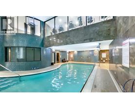 A swimming pool inside a building with a glass wall.