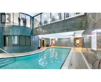 A swimming pool inside a building with a glass wall.