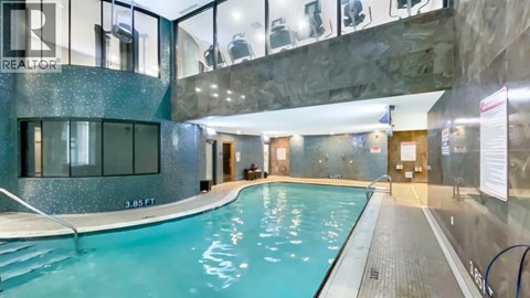 A swimming pool inside a building with a glass wall.