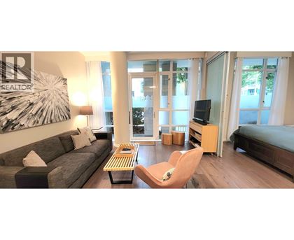 A living room with a grey couch, a wooden coffee table, a television, and a large painting on the wall.
