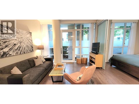 A living room with a grey couch, a wooden coffee table, a television, and a large painting on the wall.