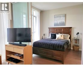 A bedroom with a bed, nightstand, and television.