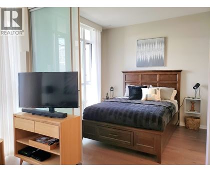 A bedroom with a bed, nightstand, and television.