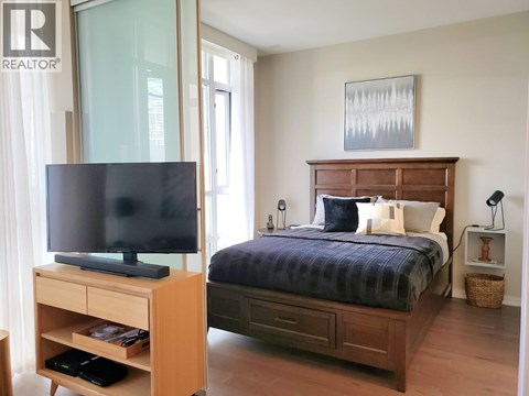 A bedroom with a bed, nightstand, and television.