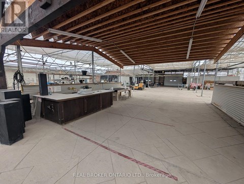 A large, empty warehouse with a high ceiling and wooden beams.