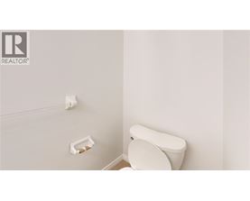 A white toilet in a bathroom with a roll of toilet paper on the wall.