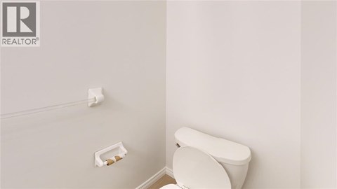A white toilet in a bathroom with a roll of toilet paper on the wall.