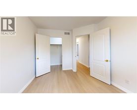 A white door is open to a hallway with wood floors.